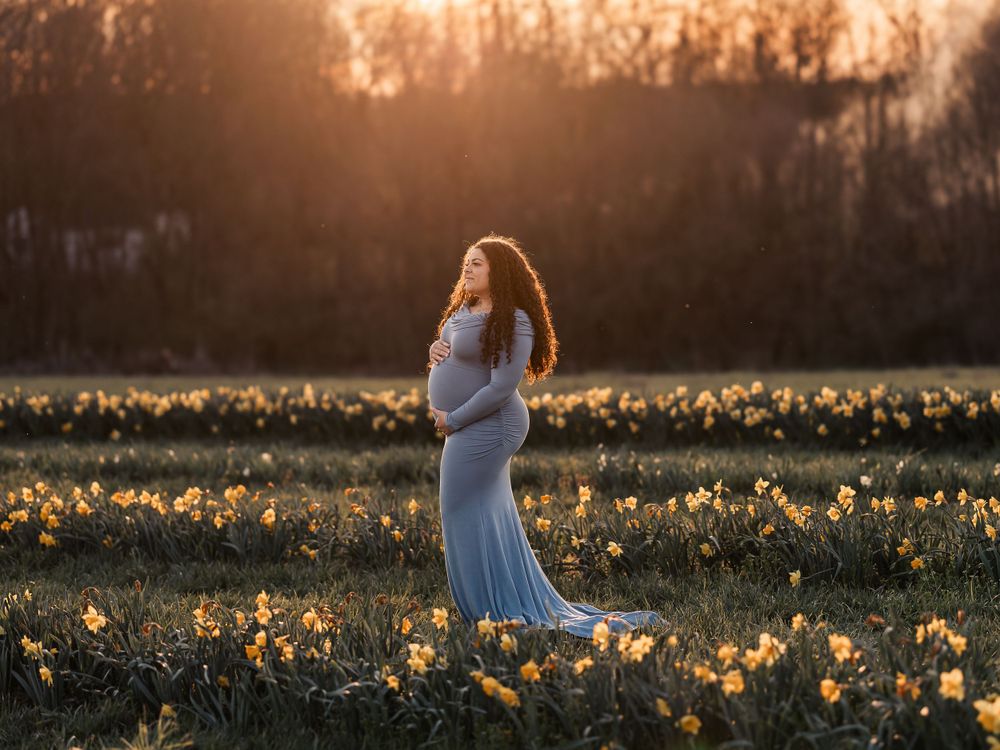 Blue dress twirling through a field of daffodils at golden hour.