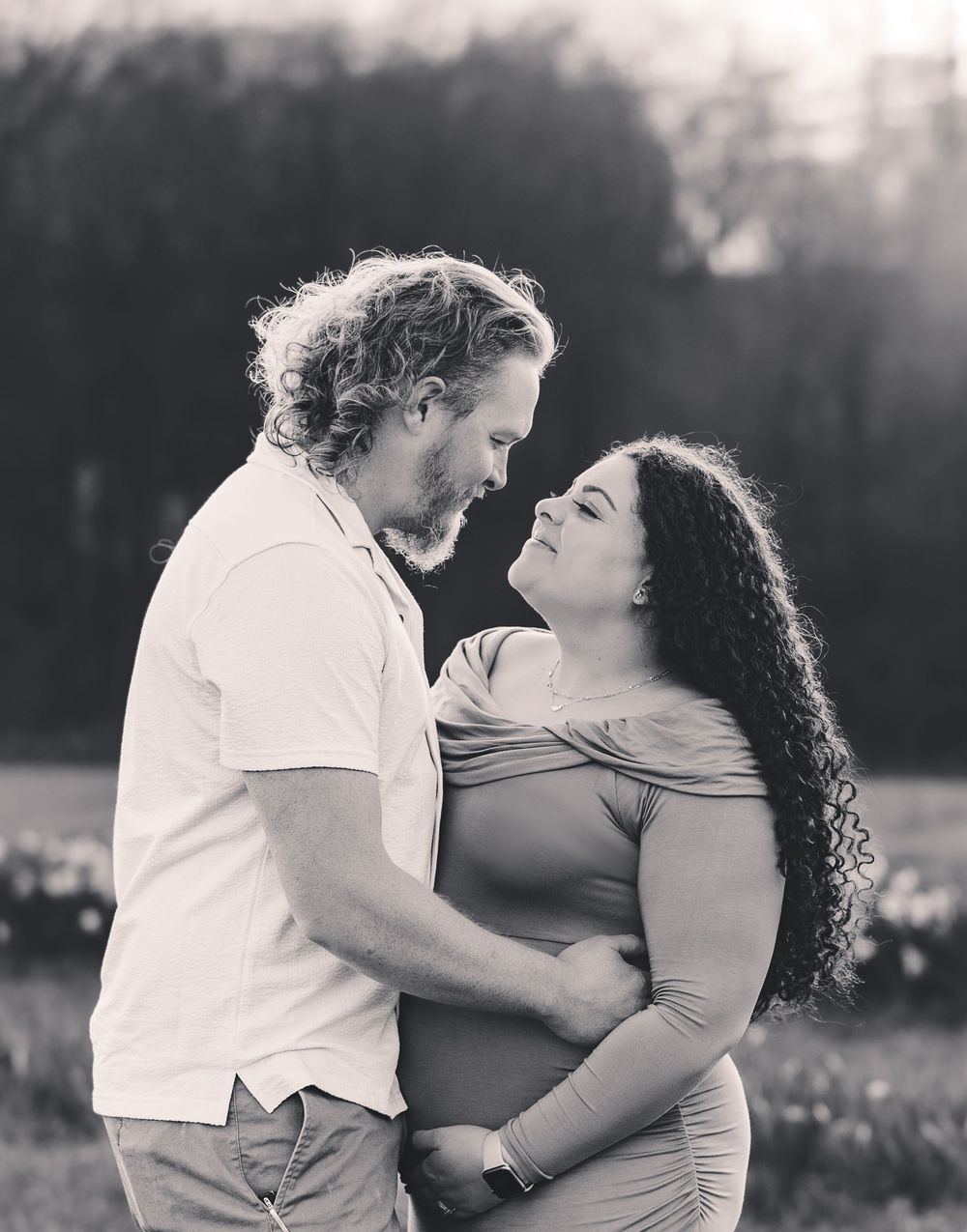 Romantic black and white portraits show tender moments between a couple in a field.