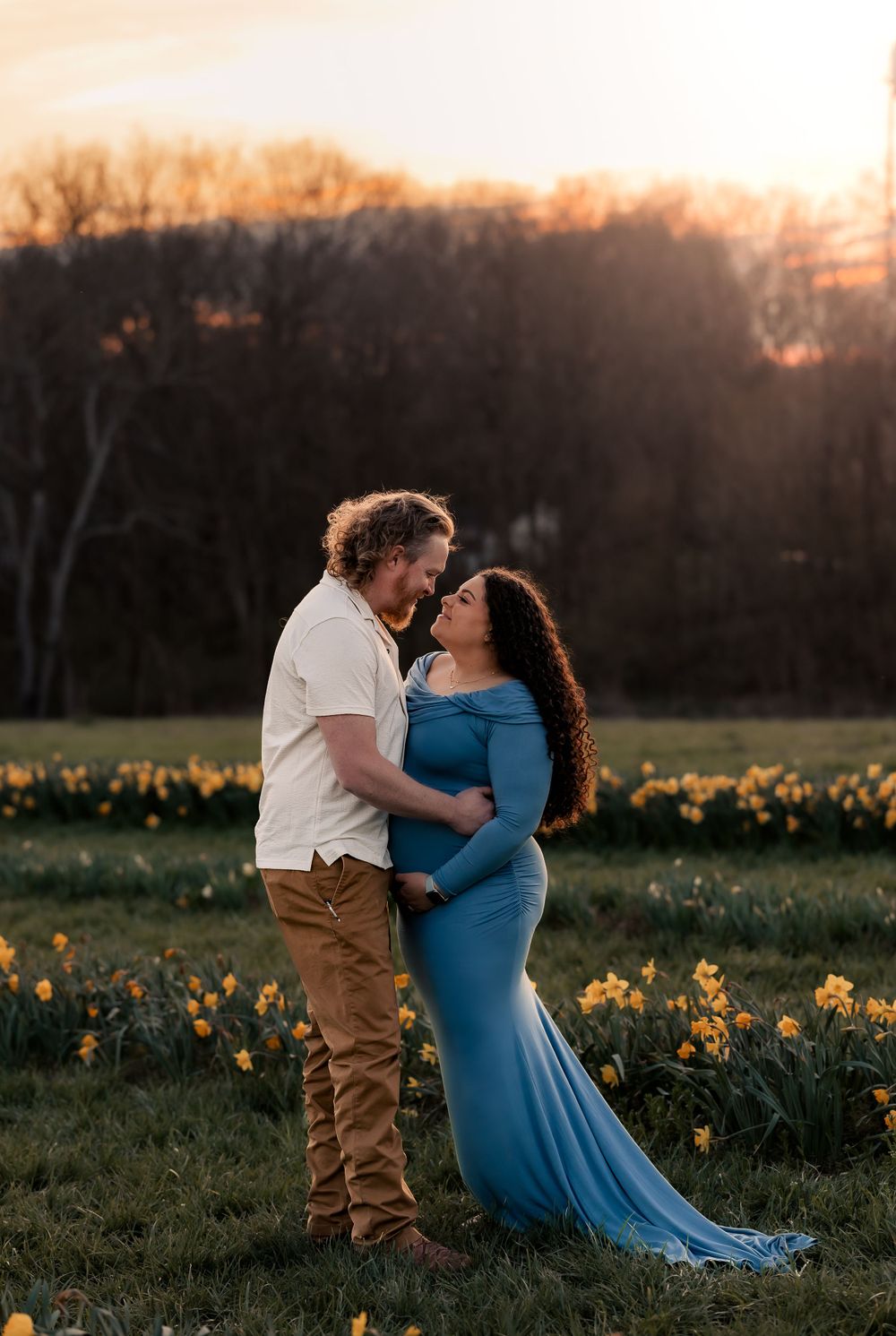 A couple shares romantic poses in a daffodil field during golden hour.