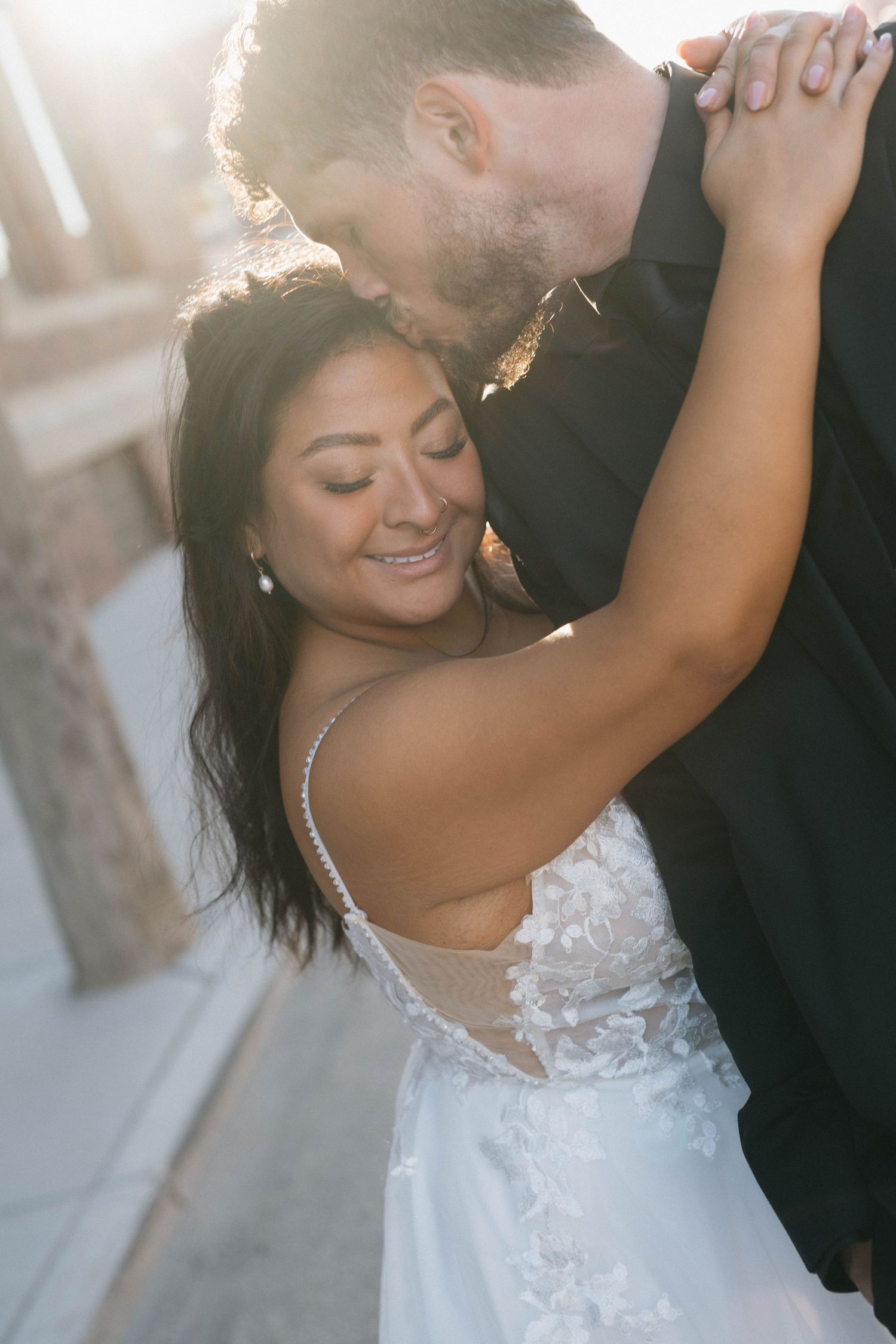 Romantic sunlit portrait of newlyweds sharing an intimate dance moment.