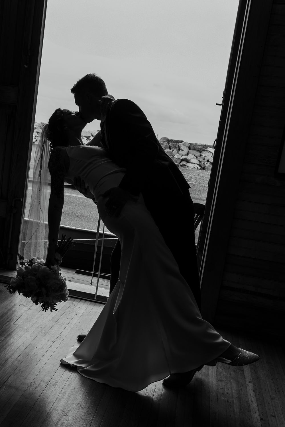 Silhouetted figures in dramatic dance pose framed by doorway during wedding celebration.
