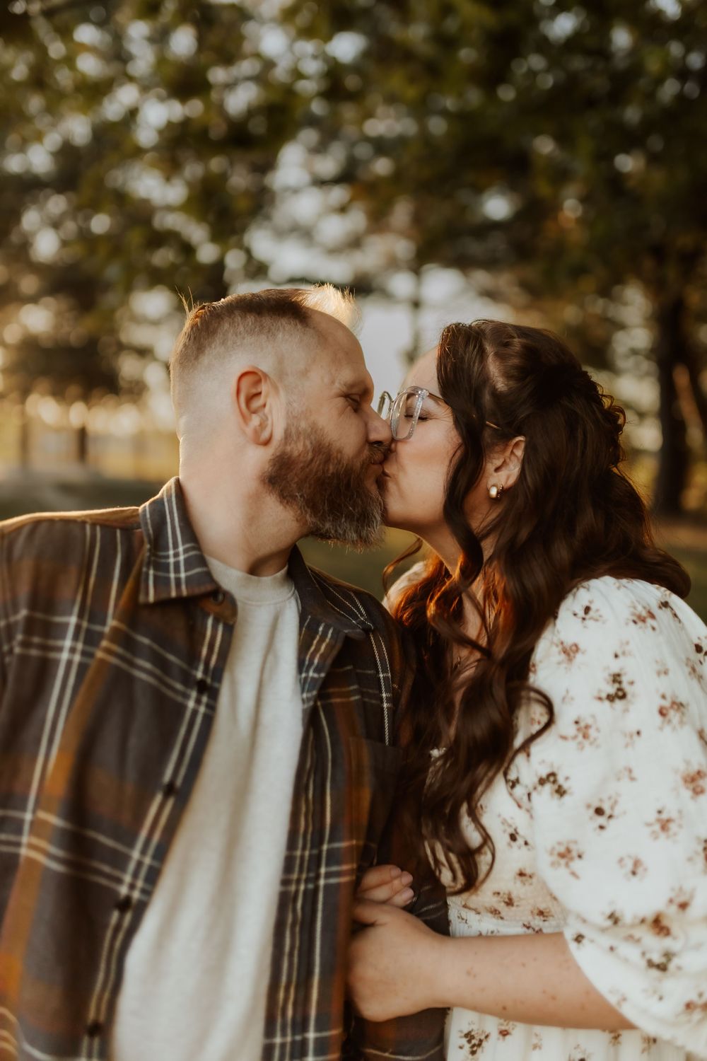 A couple embracing and sharing tender moments during an outdoor autumn photoshoot.