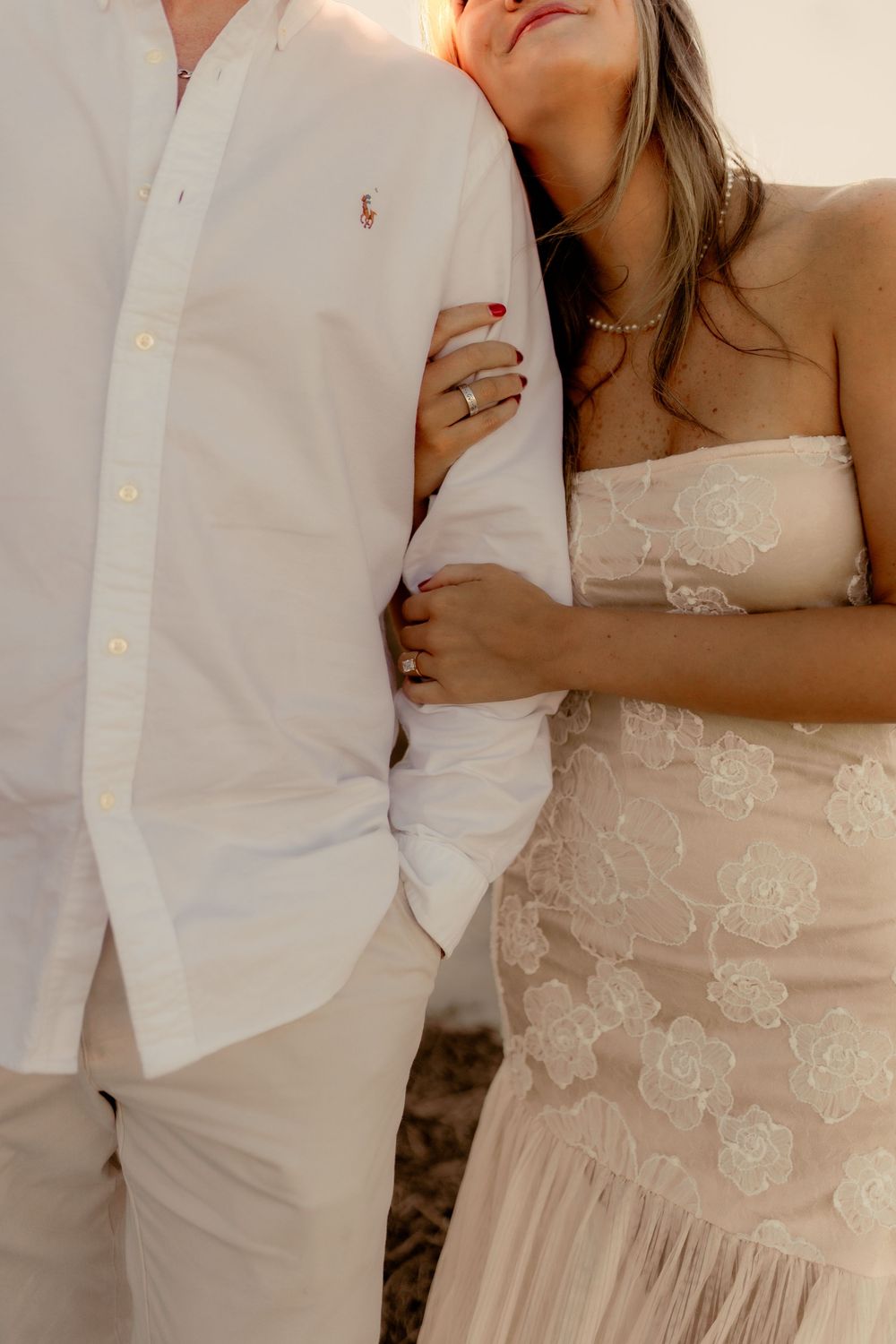 Close-up of couple in white wedding attire showing dress details and romantic embrace.