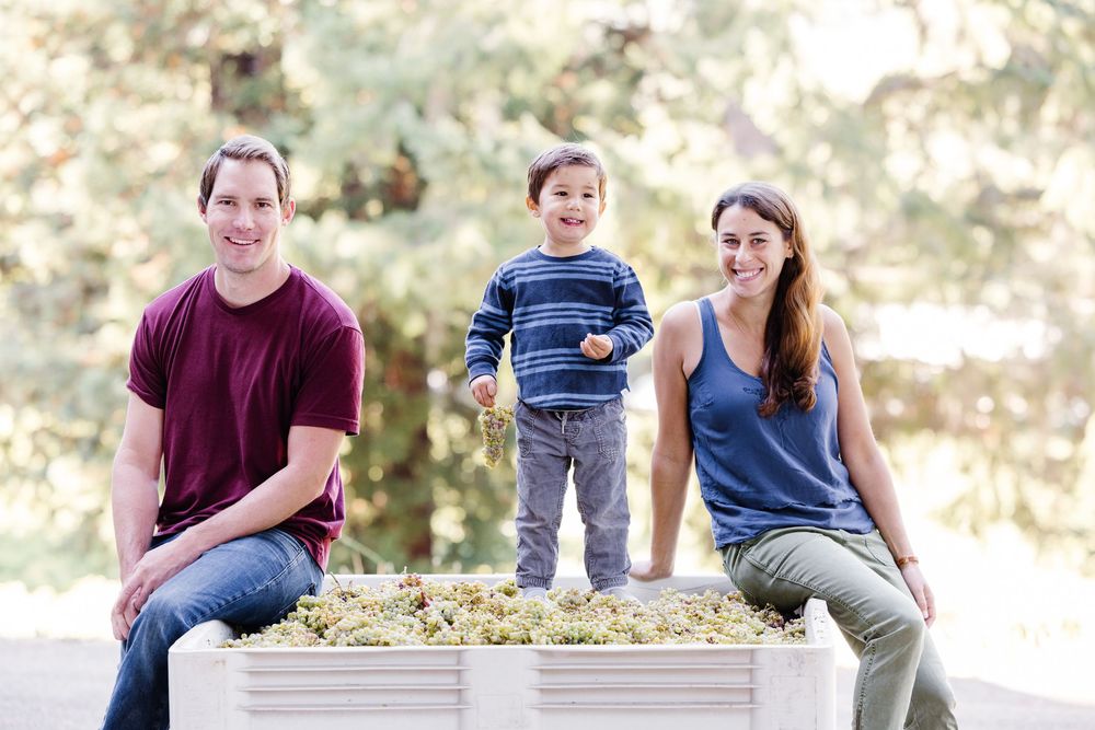 A group of people sitting and laughing together outdoors in a casual setting with natural lighting.