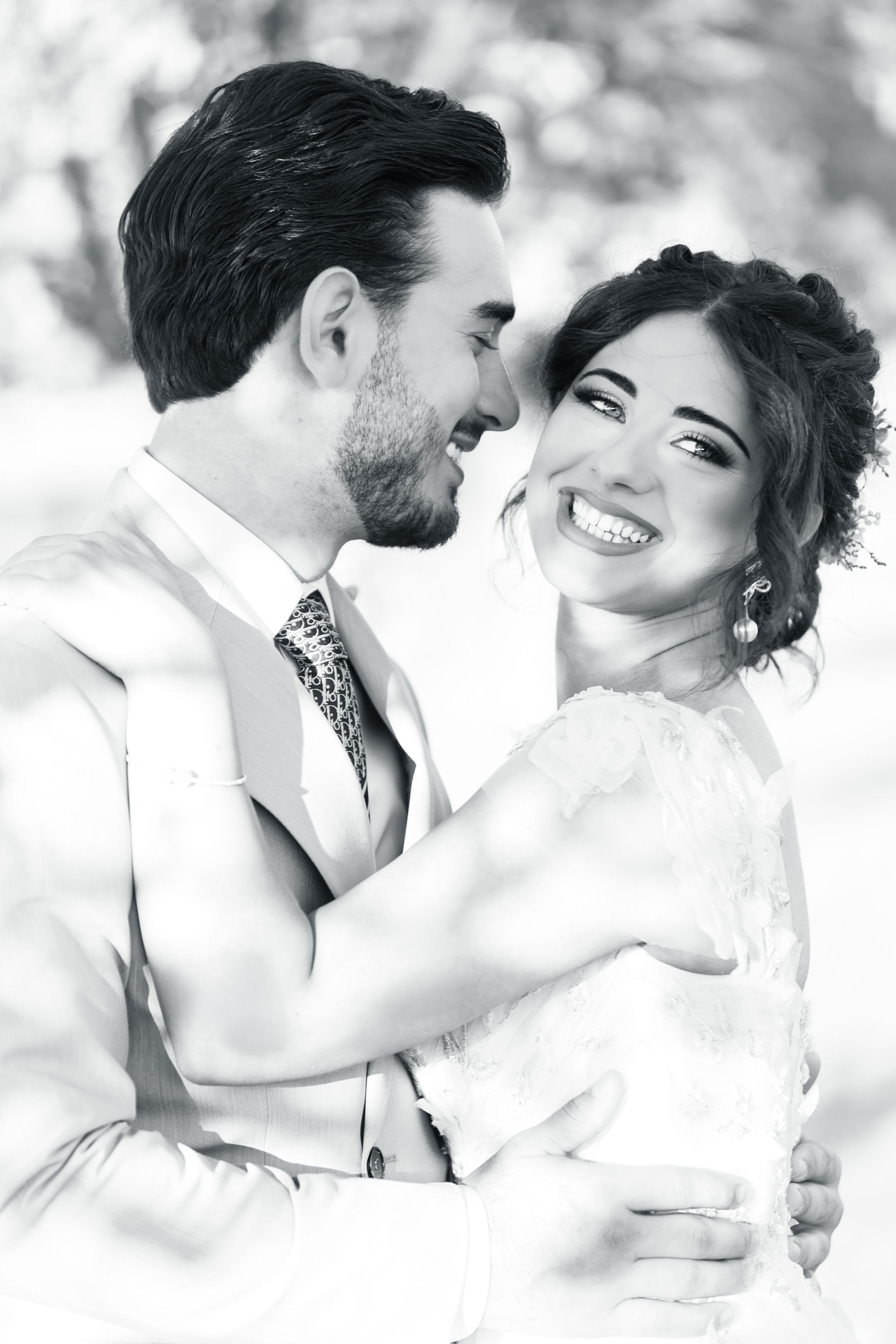 Joyful black and white portrait of a newly engaged couple embracing and laughing together on their wedding day.