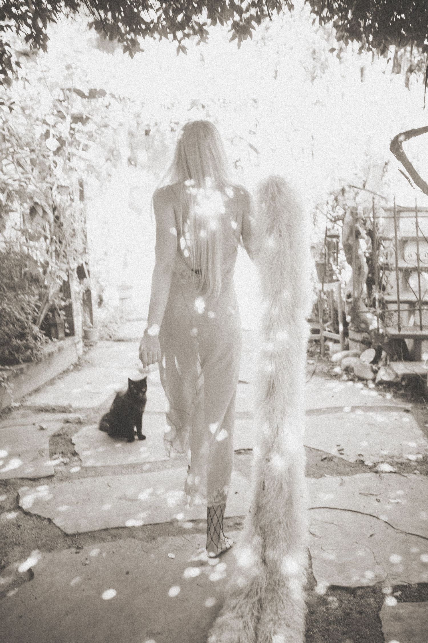 Ethereal black and white photograph showing ghostly figures in a garden setting.