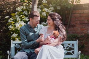 A family shares a tender moment on a garden bench surrounded by white flowers.
