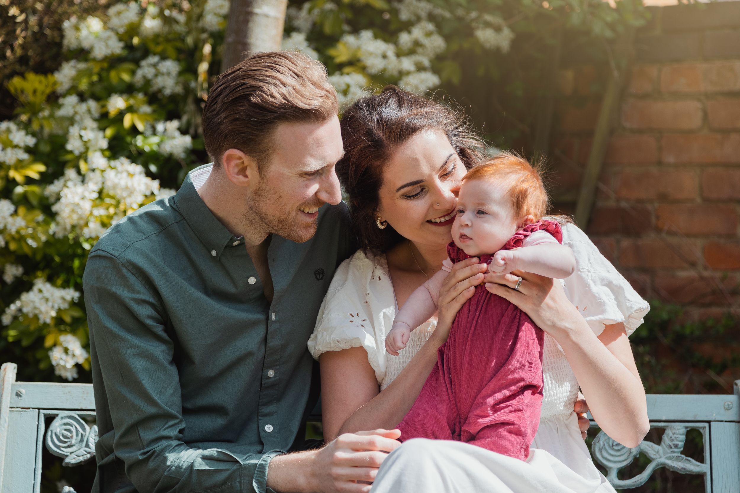 A family enjoying a sunny moment together on an outdoor bench.