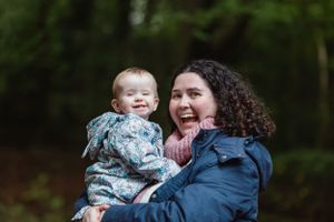 A tender moment between parent and child outdoors with natural greenery.