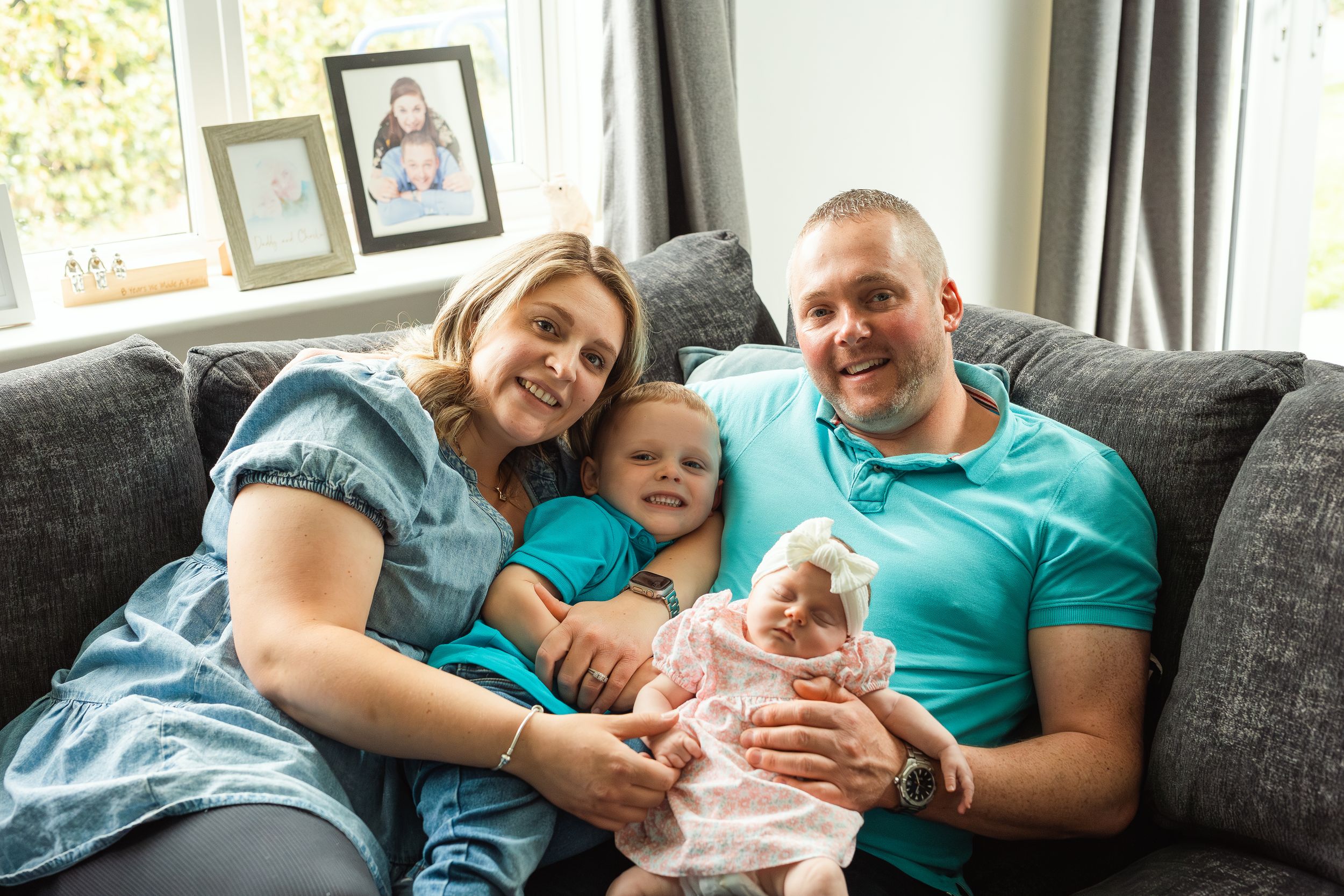 Family sharing joyful moment together on grey couch in living room.