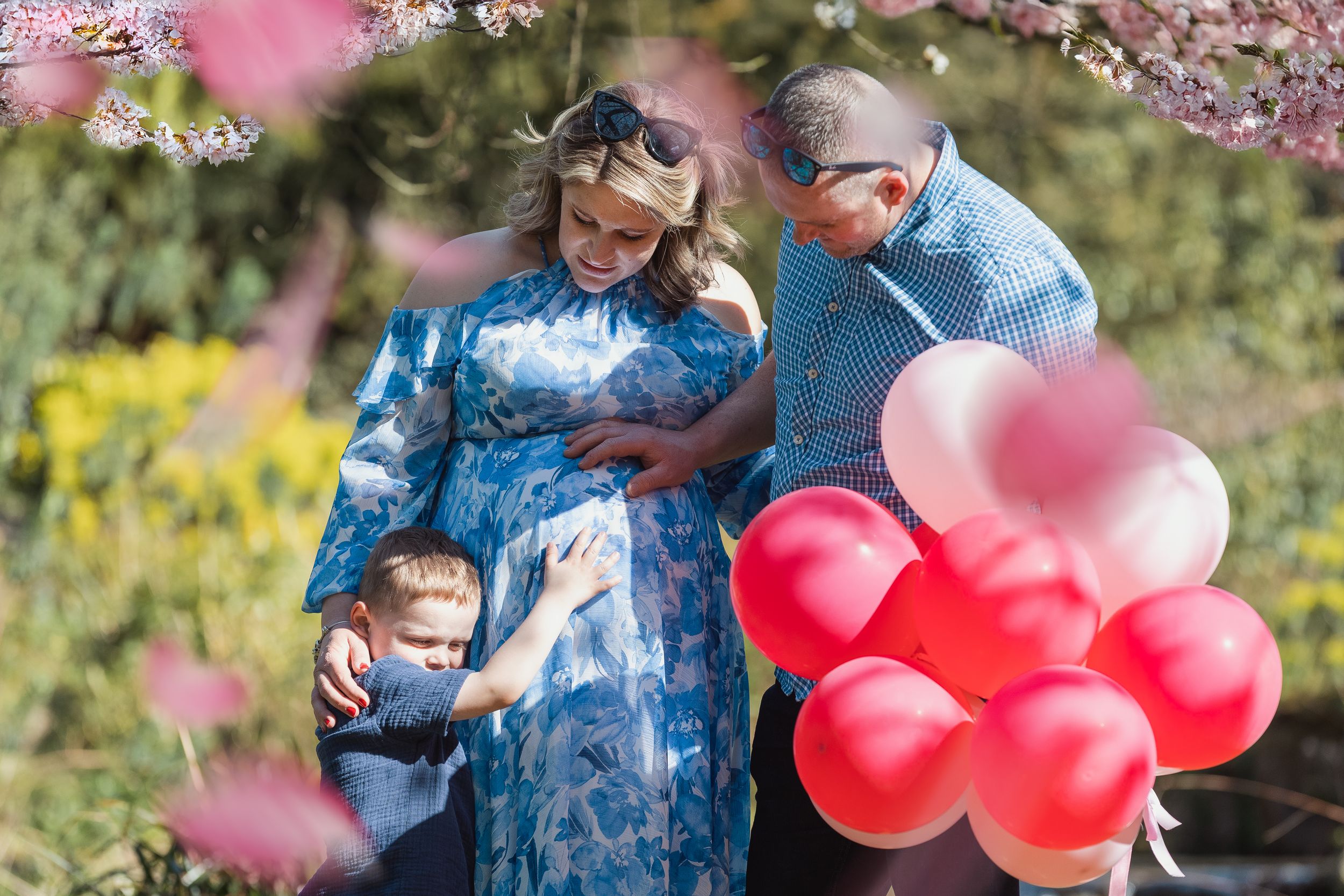 Family posing under blooming cherry trees in spring garden.