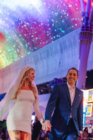 A downtown Vegas elopement with bride and groom walking under the colorful lights of the Freemont Street Experience.