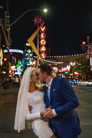 A romantic wedding photo on Fremont Street in downtown Las Vegas with illuminated neon signs in the background.