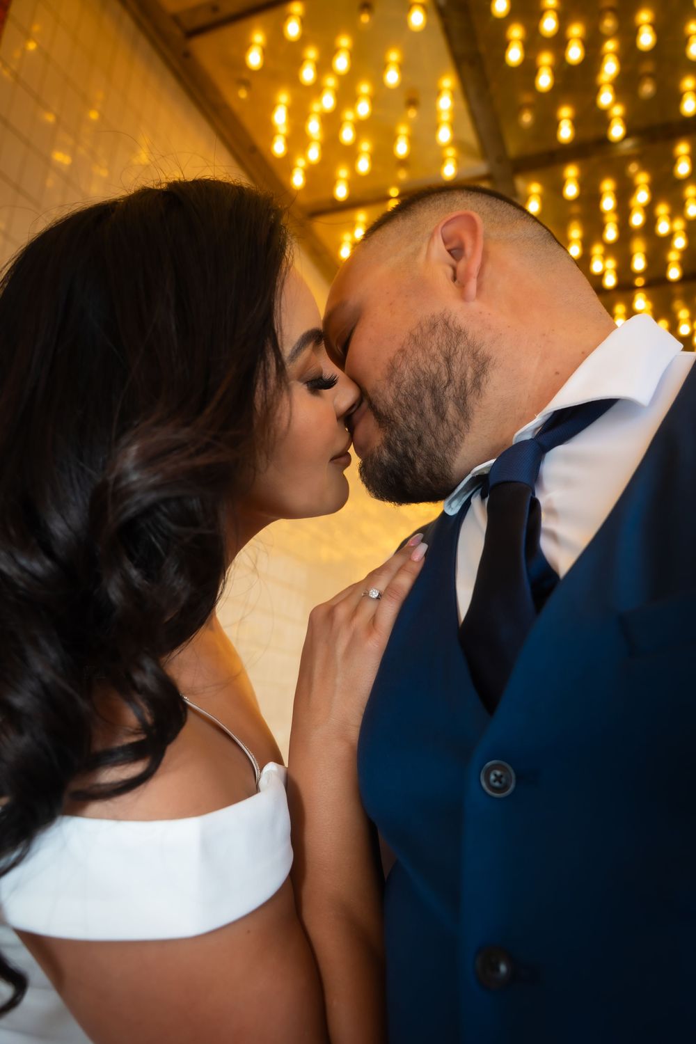 Romantic wedding couple sharing an intimate moment under warm glowing lights at their reception.