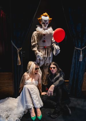 Pennywise stands behind rock 'n roll bride and groom during elopement photos in Las Vegas Halloween suite.