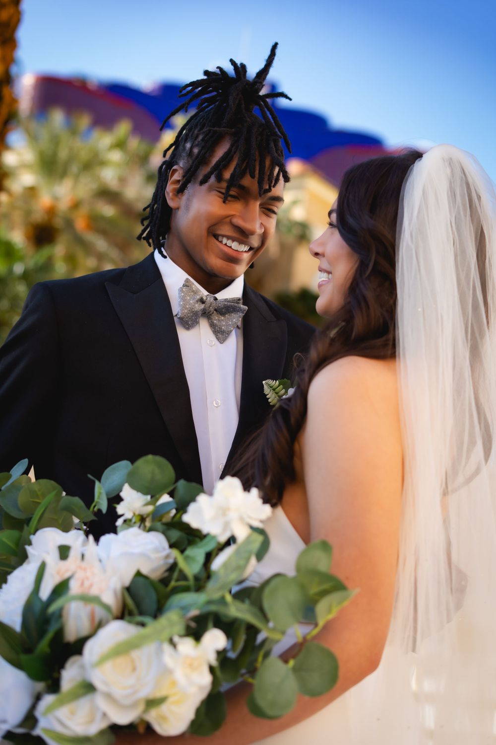 A tender moment between newlyweds at an Las Vegas elopement with white floral bouquet and greenery details.