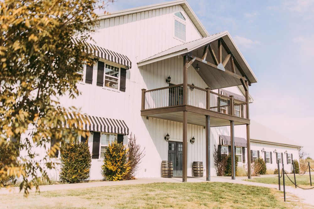 Exterior view of a white wedding venue with striped awnings and multiple balconies.