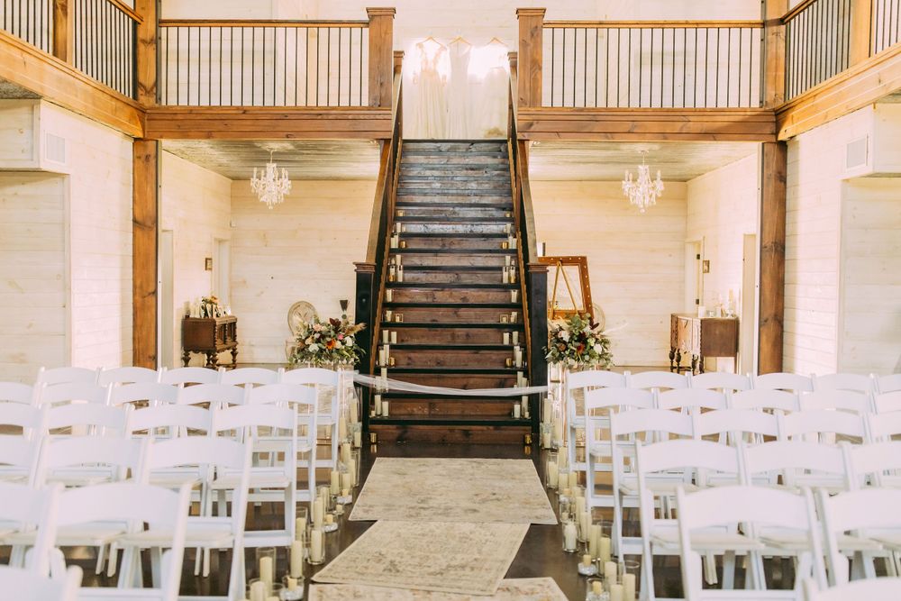 Indoor wedding ceremony space with grand staircase and white chairs lined up in rows.