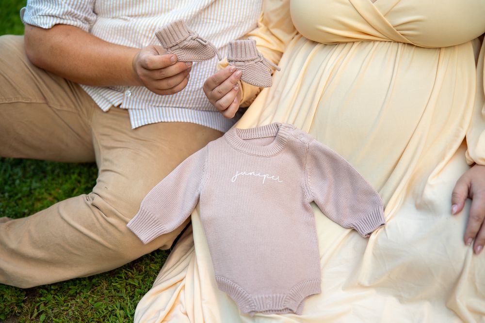 A person wearing khaki pants and a white shirt sits on grass during an outdoor gathering.