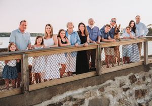 A large family standing together on a waterfront dock during sunset by the ocean.
