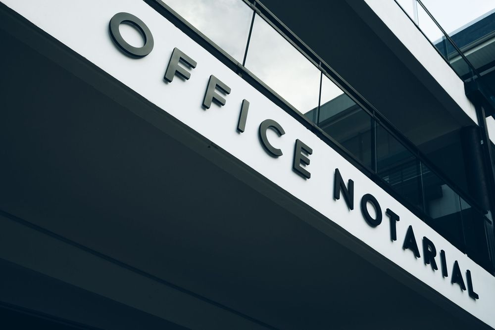 Close-up of a modern notarial office building exterior sign reading Office Notarial in bold letters.