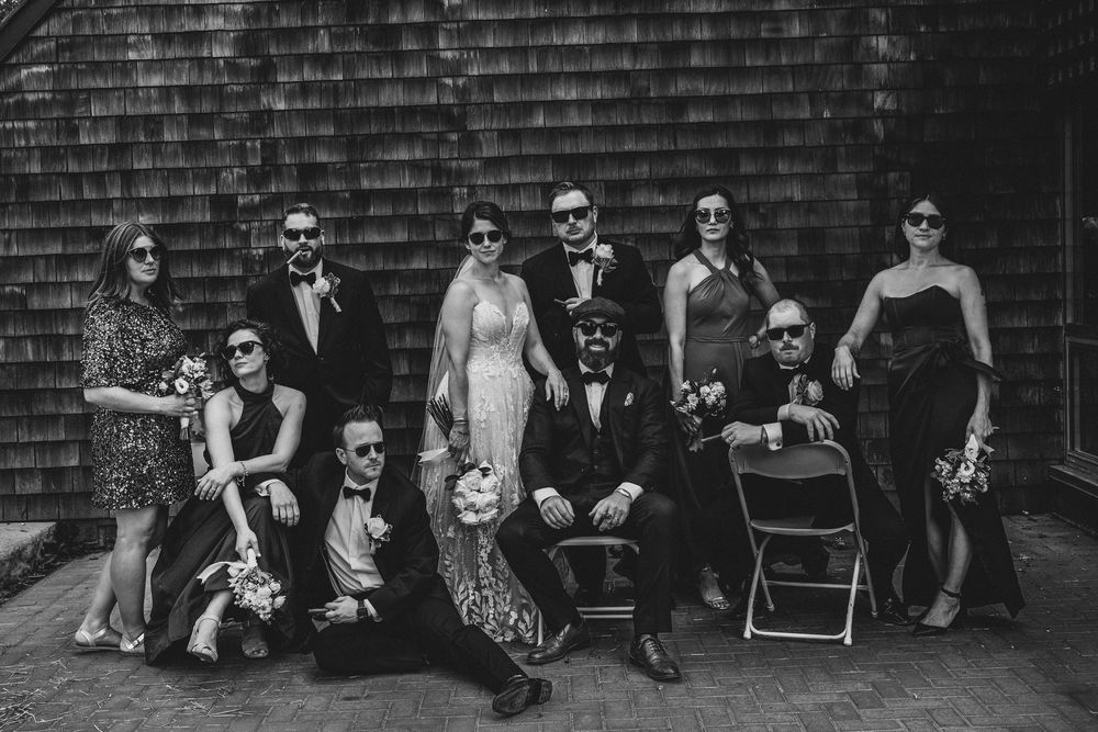 Wedding guests seated in a row against a brick wall outdoors.