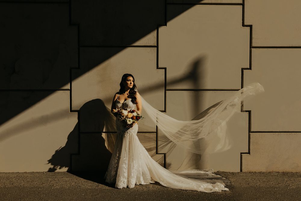 Artistic wedding photo with dramatic shadows against geometric wall architecture.