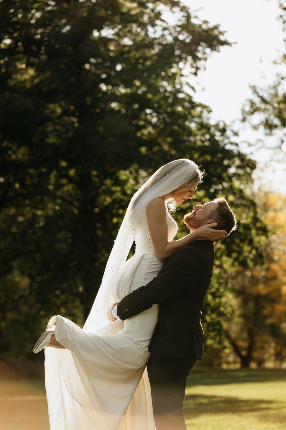 Couple shares romantic dance pose in sunlit garden setting.