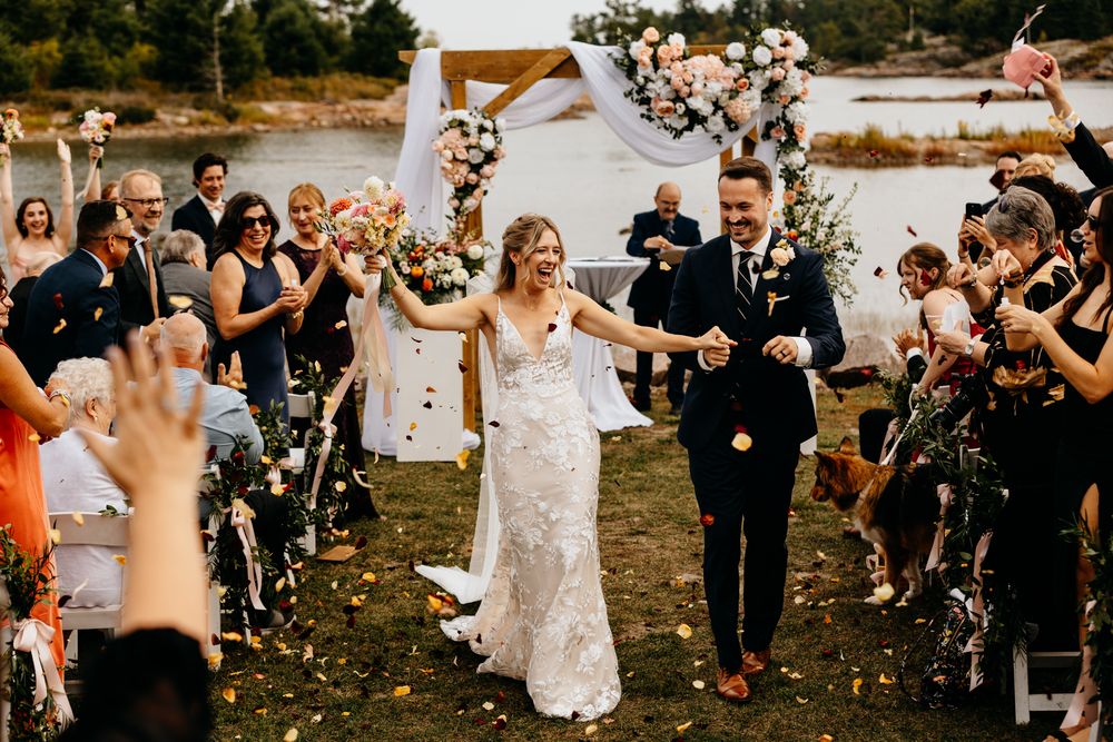 Wedding guests throw confetti during an outdoor celebration.