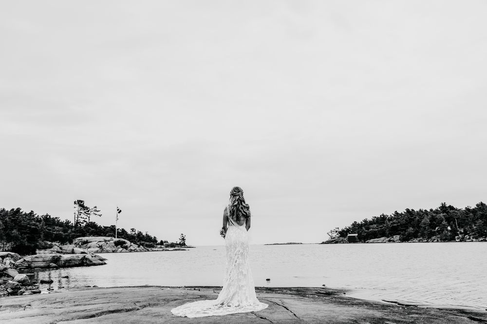 Minimalist black and white coastal landscape with lighthouse in distance.