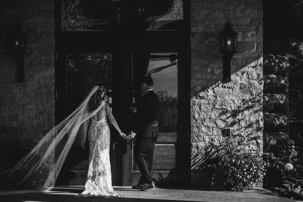 Silhouettes of a wedding celebration against a stone wall backdrop.
