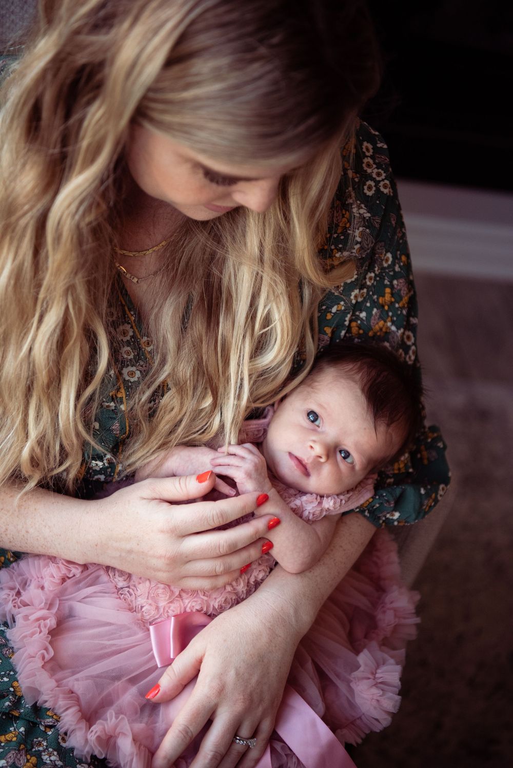 A baby in a pink tutu dress snuggles close while being held in a tender moment.