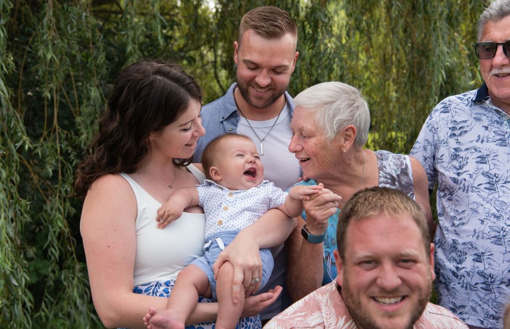 A candid family moment captured outdoors with everyone laughing together.