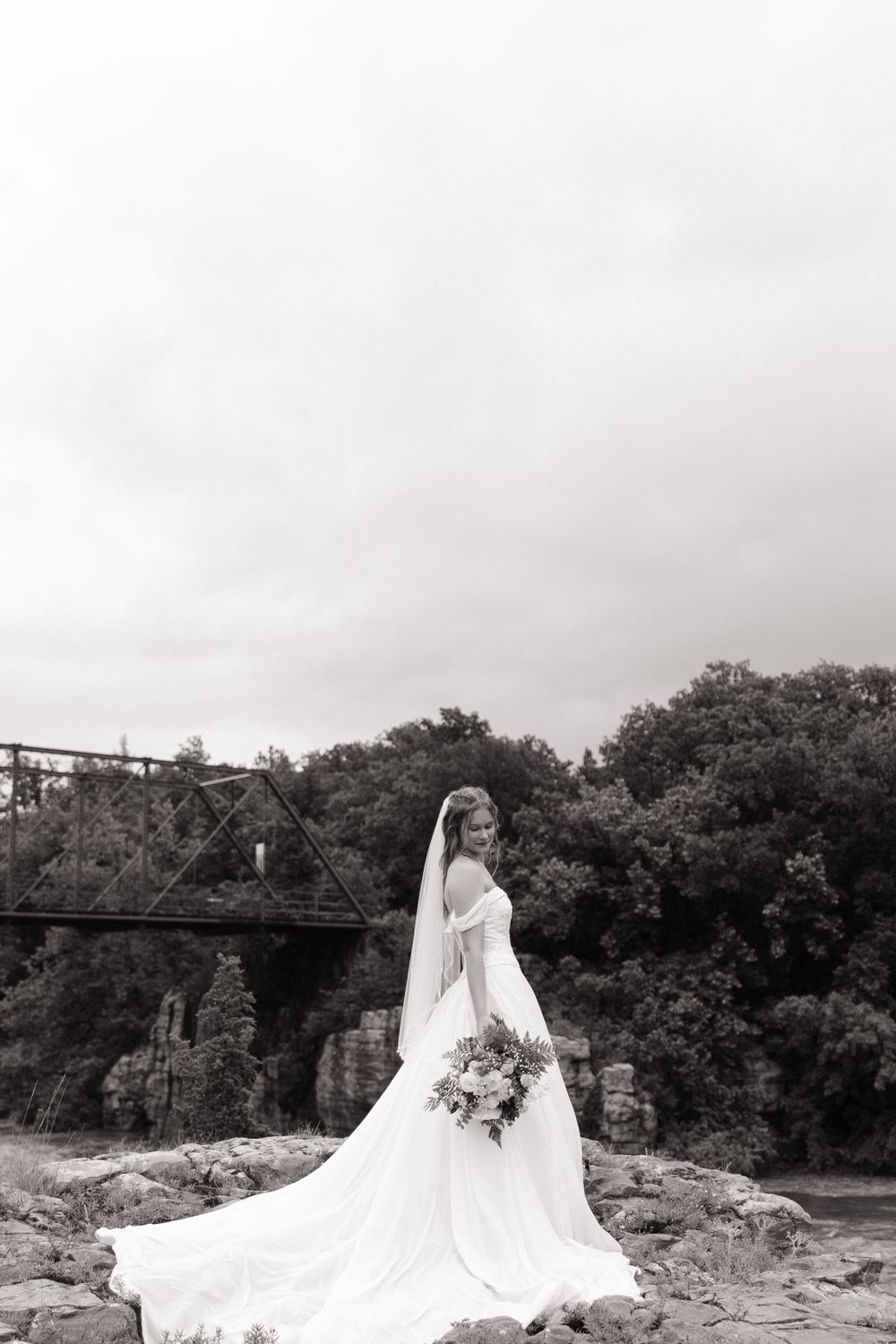 Dramatic black and white bridal portrait near rustic bridge.