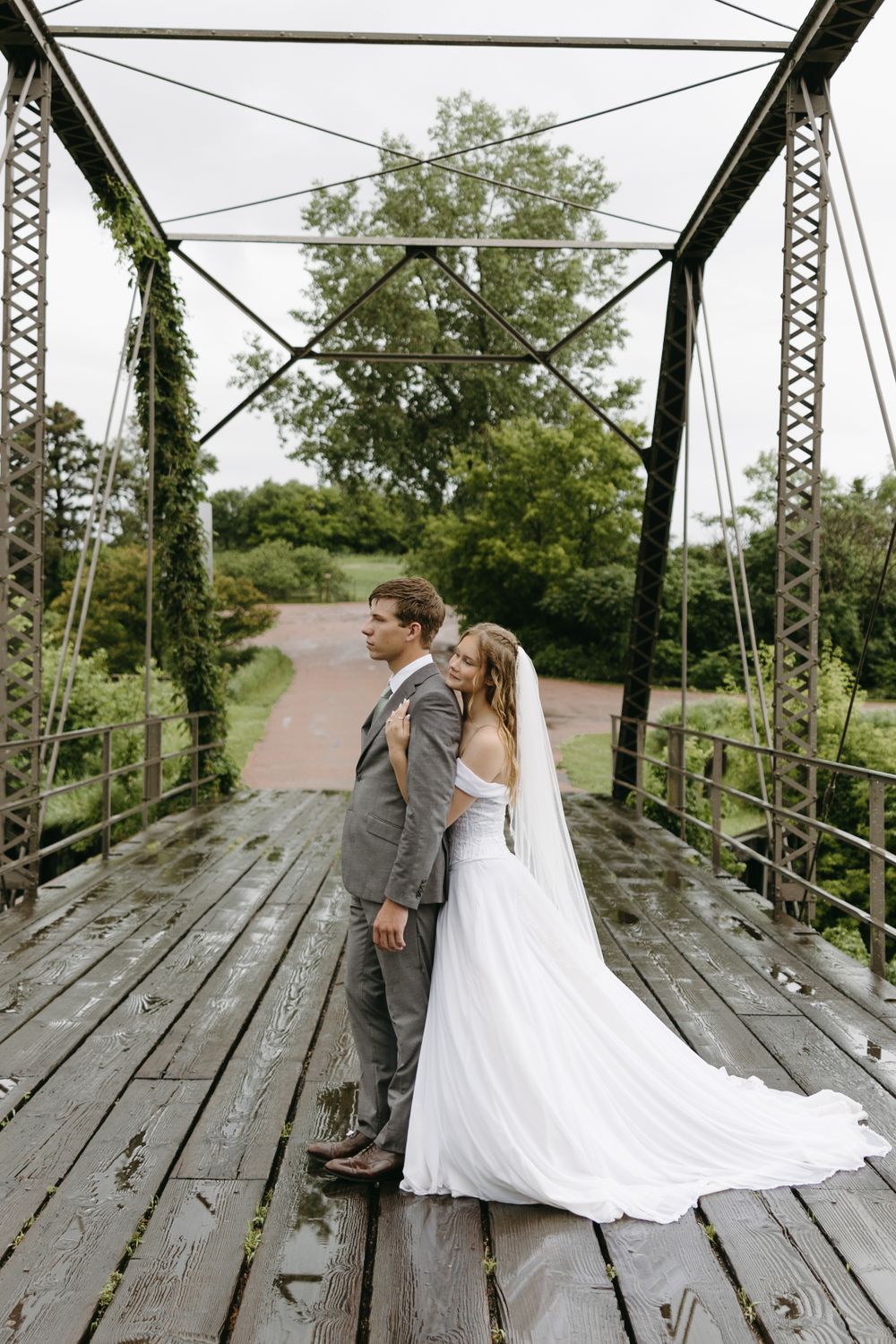 Romantic couple pose on vintage bridge in wedding attire.