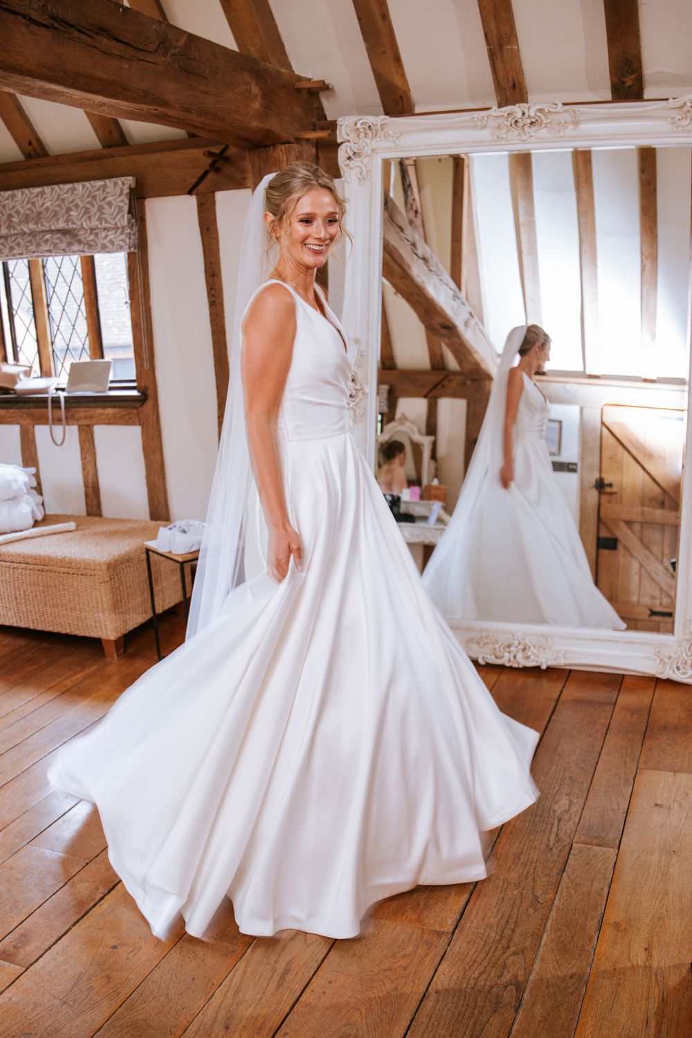 A happy bride ready for the ceremony, taking a look in a mirror and doing a joyful twirl.