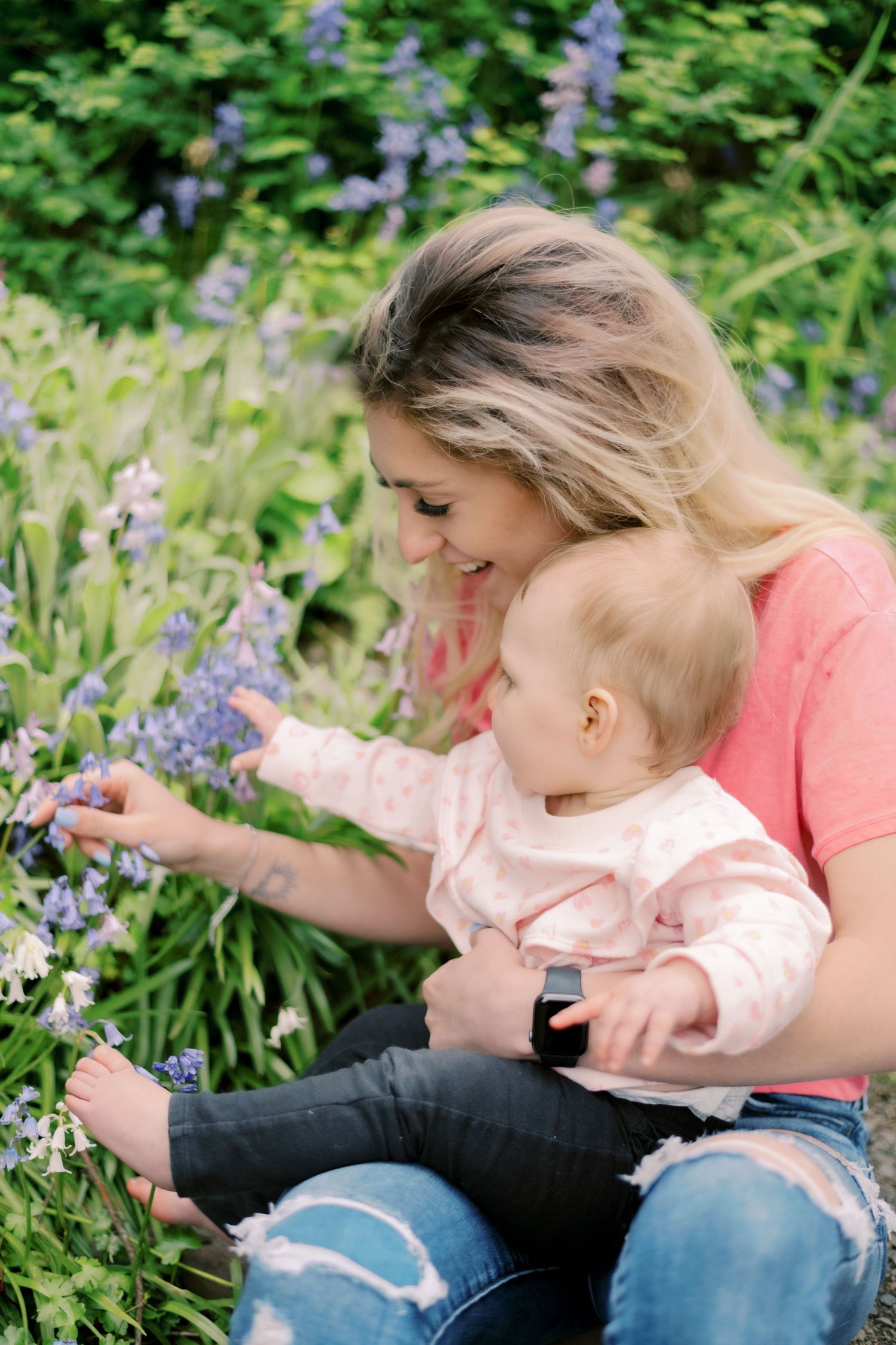 Parent and child exploring purple flowers in garden setting.