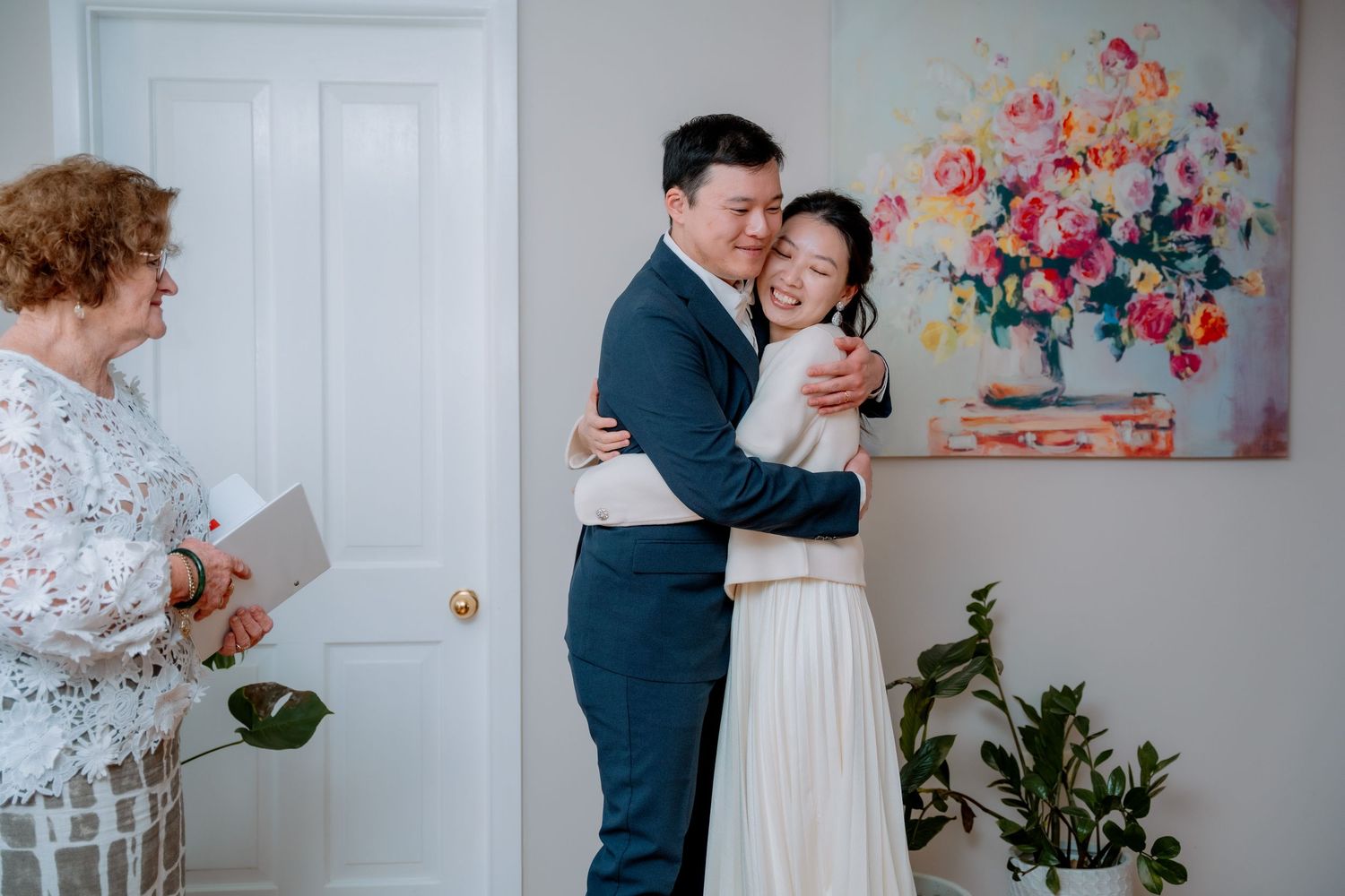 Newlyweds embrace while the celebrant smiles beside them - small elopement ceremony, Sydney elopement photographer