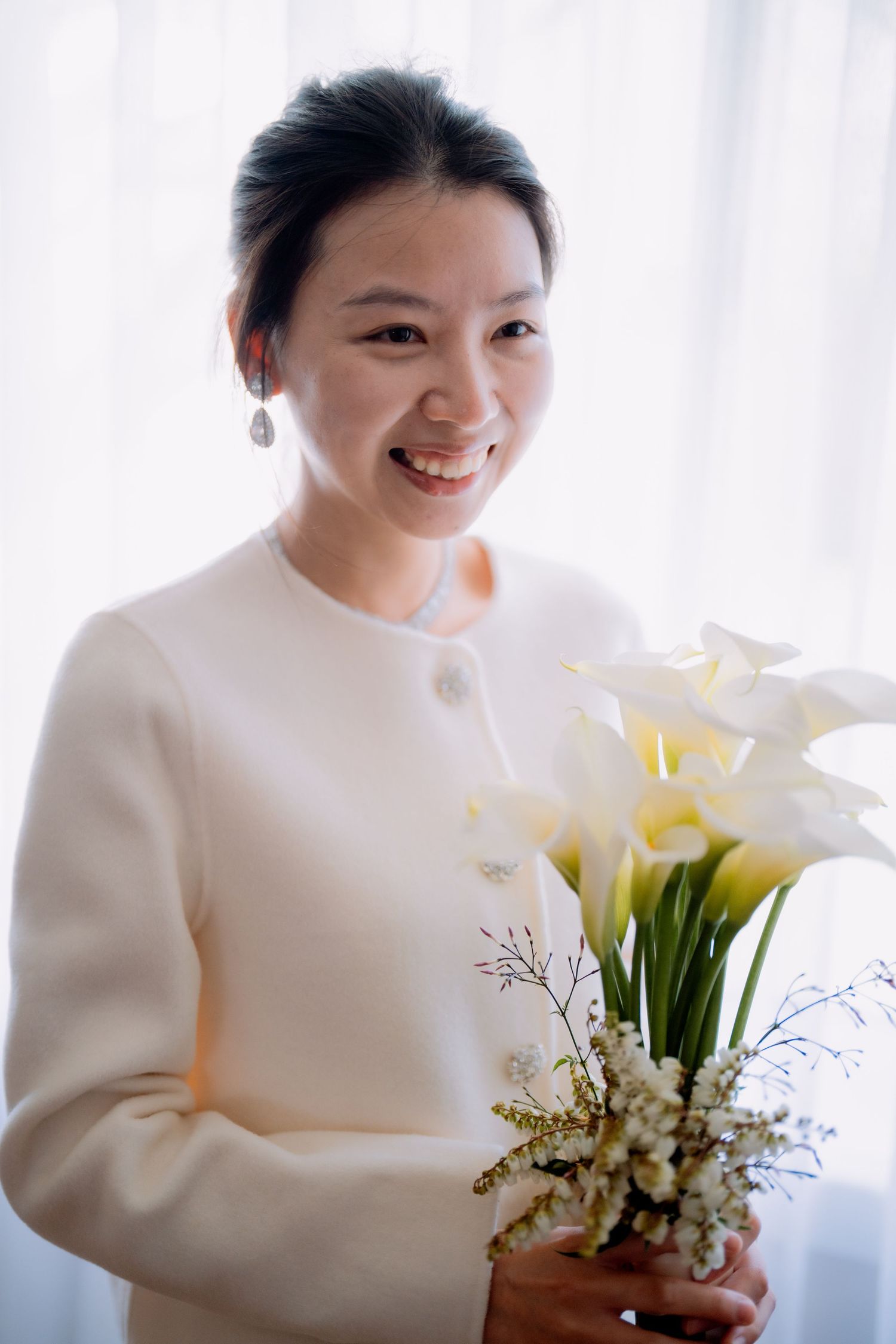 Elopement bride with pearl drop earrings holding white calla lilies by a soft window - Sydney elopement photographer