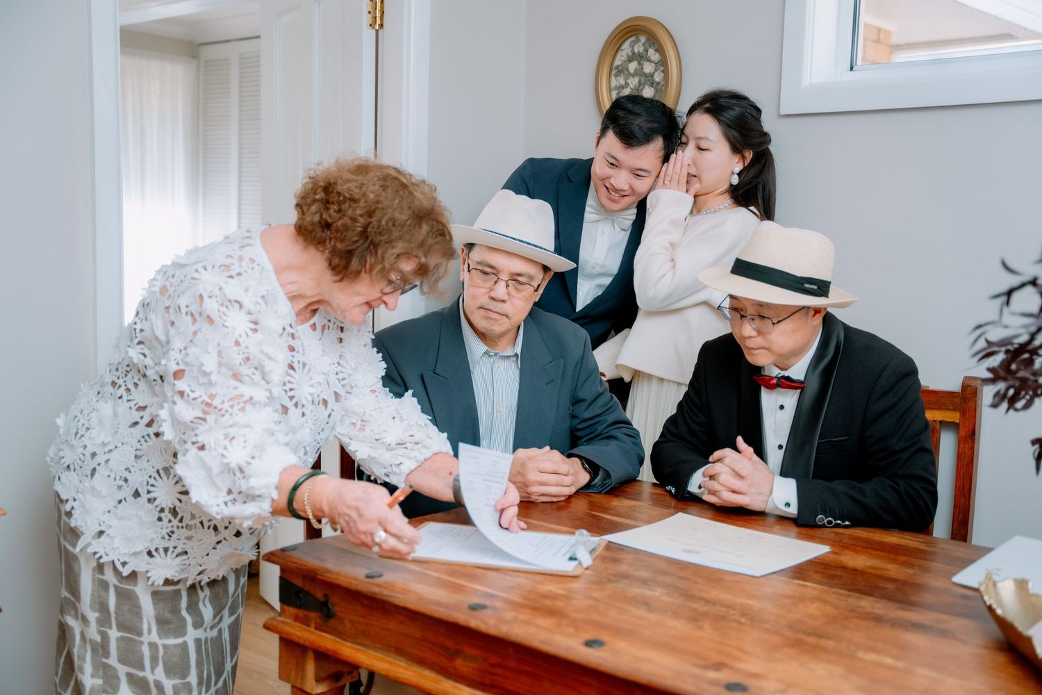 Elderly guest signs the wedding documents as the couple look on - intimate elopement ceremony in Sydney