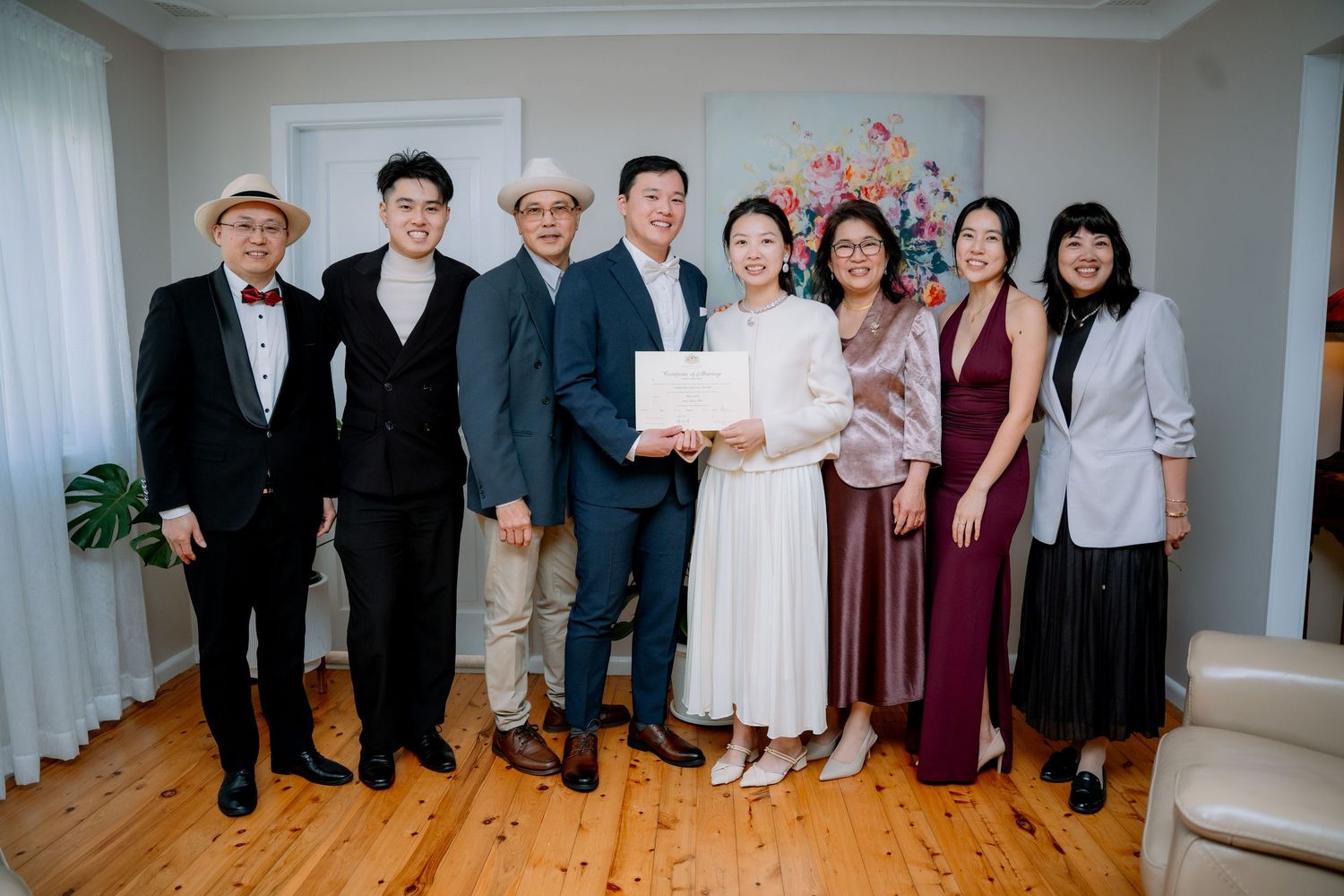 Couple with family holding the marriage certificate in a bright room - small intimate elopement celebration