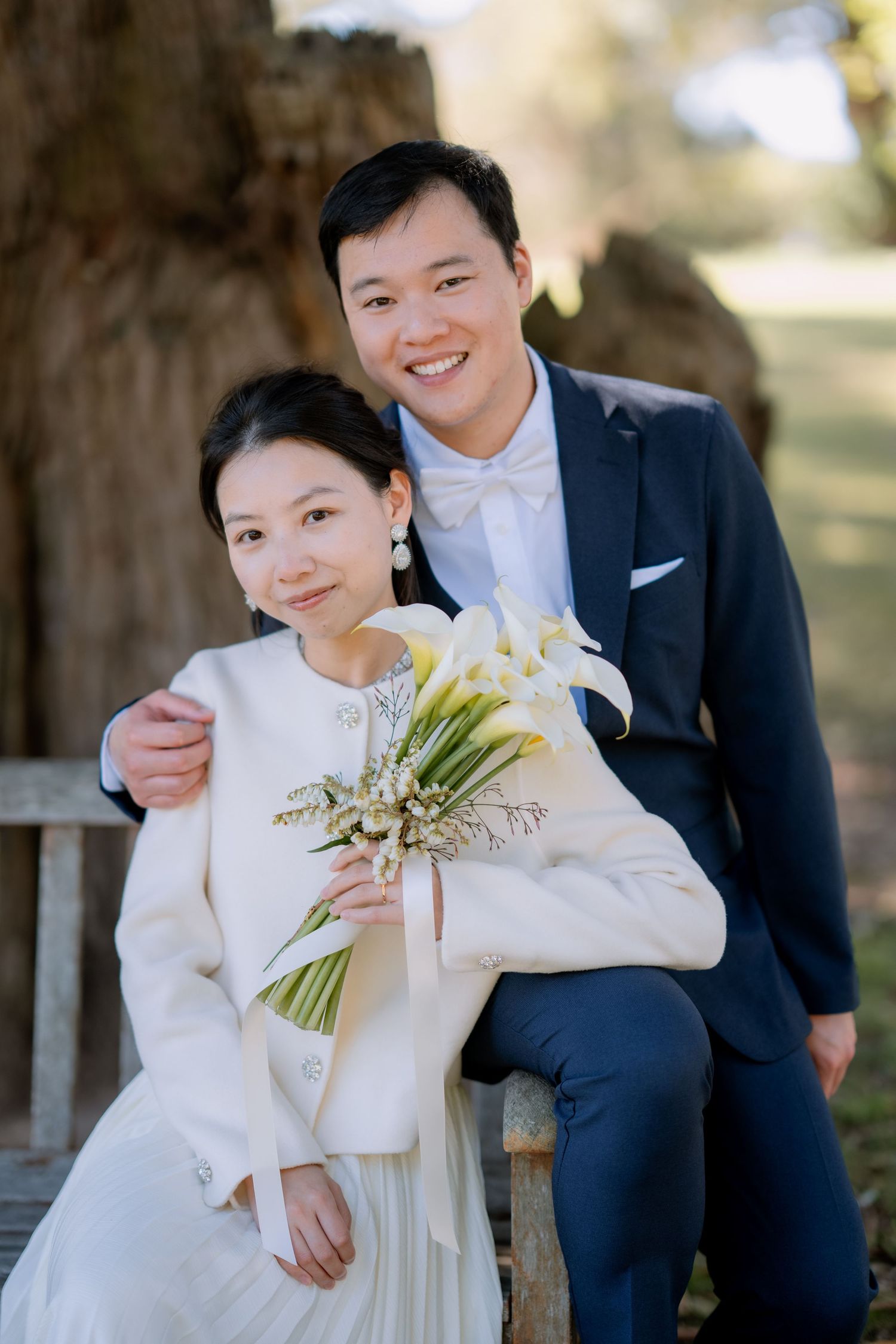 Groom embraces his bride on a wooden bench in the park - relaxed intimate elopement portrait