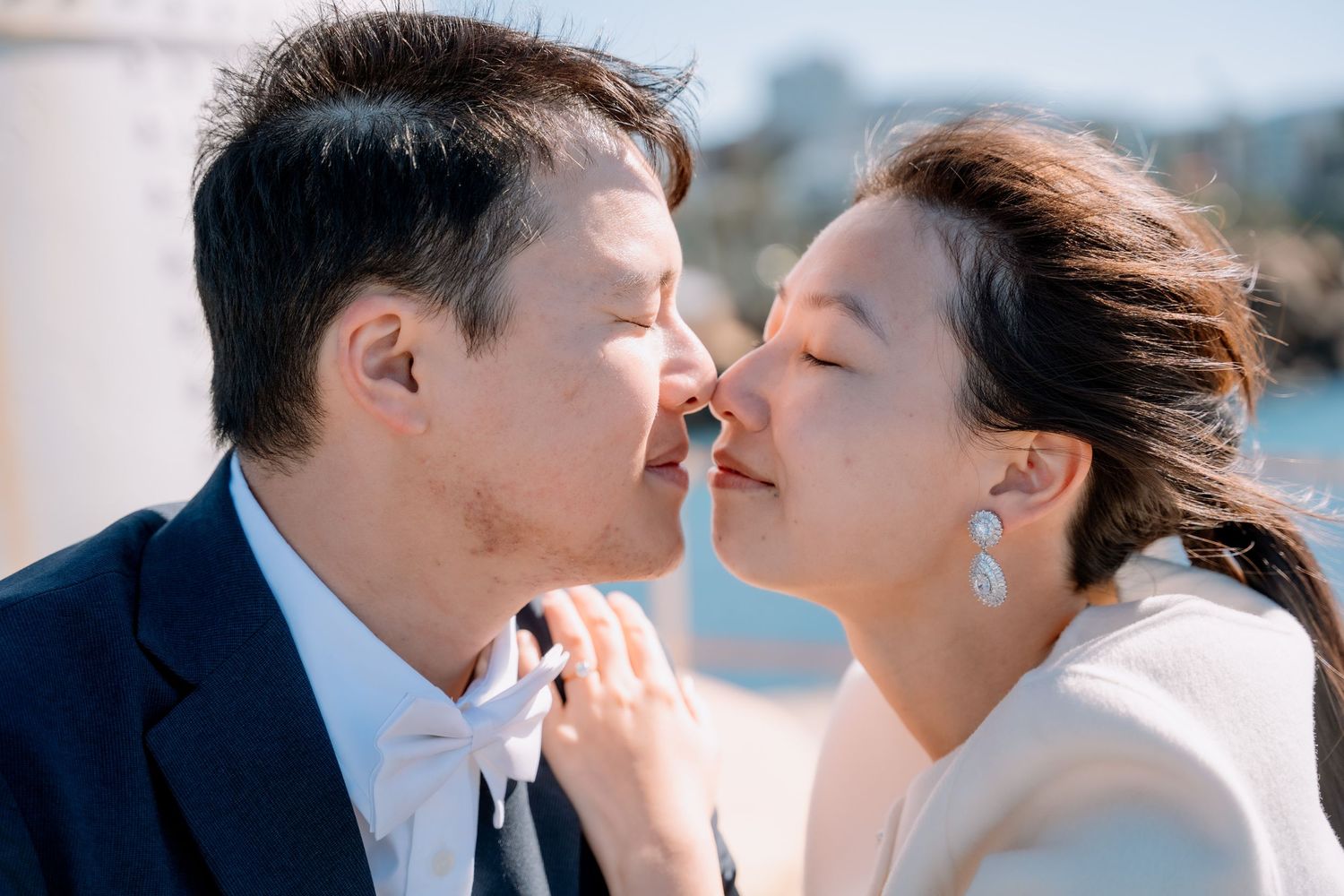 Close-up of the couple about to kiss, groom in a bow tie and bride in pearl earrings - intimate elopement portrait