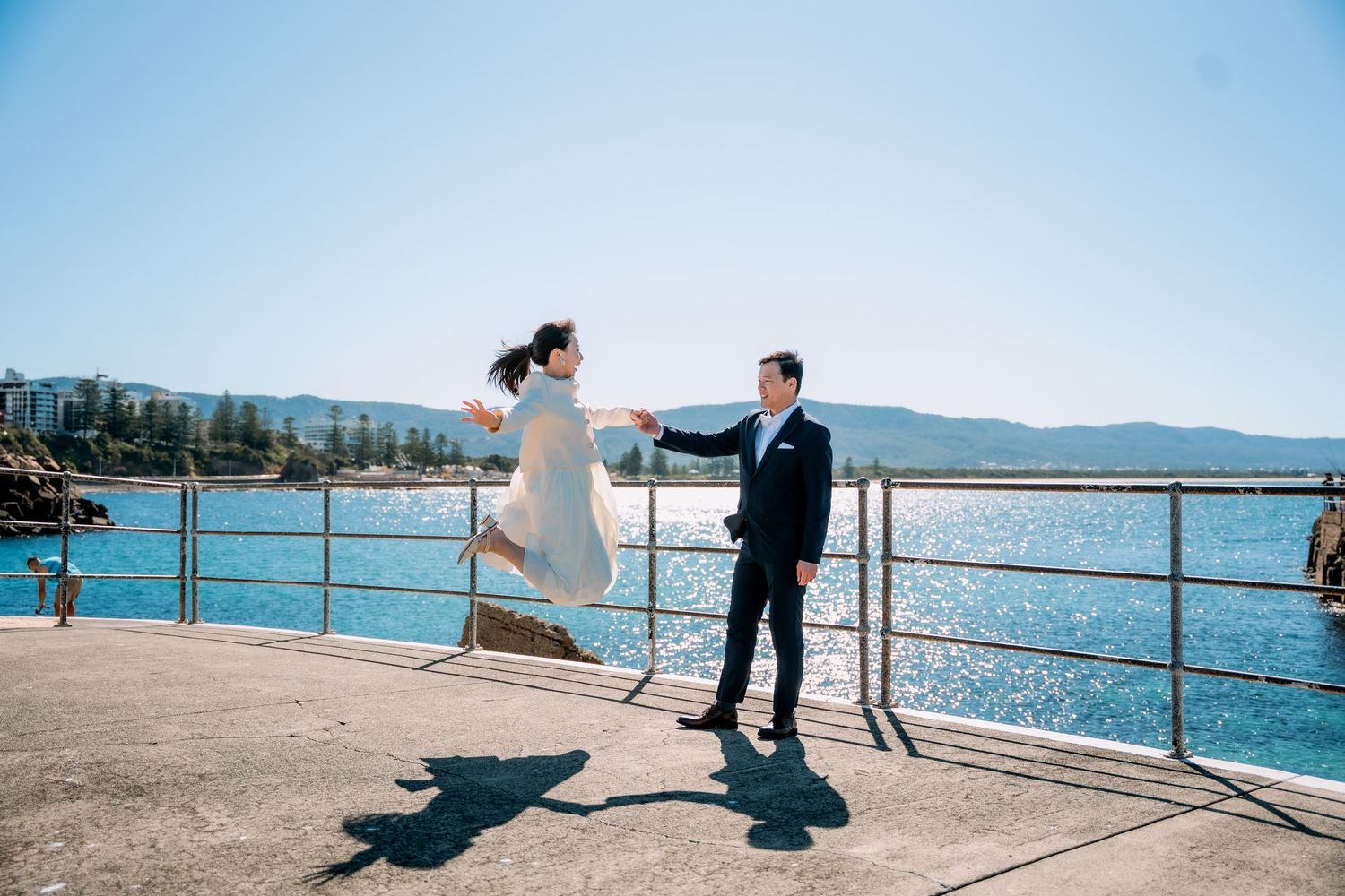 Bride leaps joyfully toward her groom on a seaside pier - fun elopement photography by Purple Bird Photo