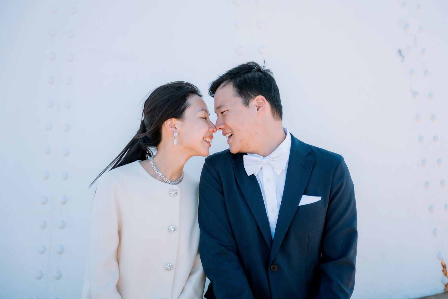 Bride in a pearl necklace touches noses with her groom in a navy bow tie - Sydney elopement photographer Purple Bird