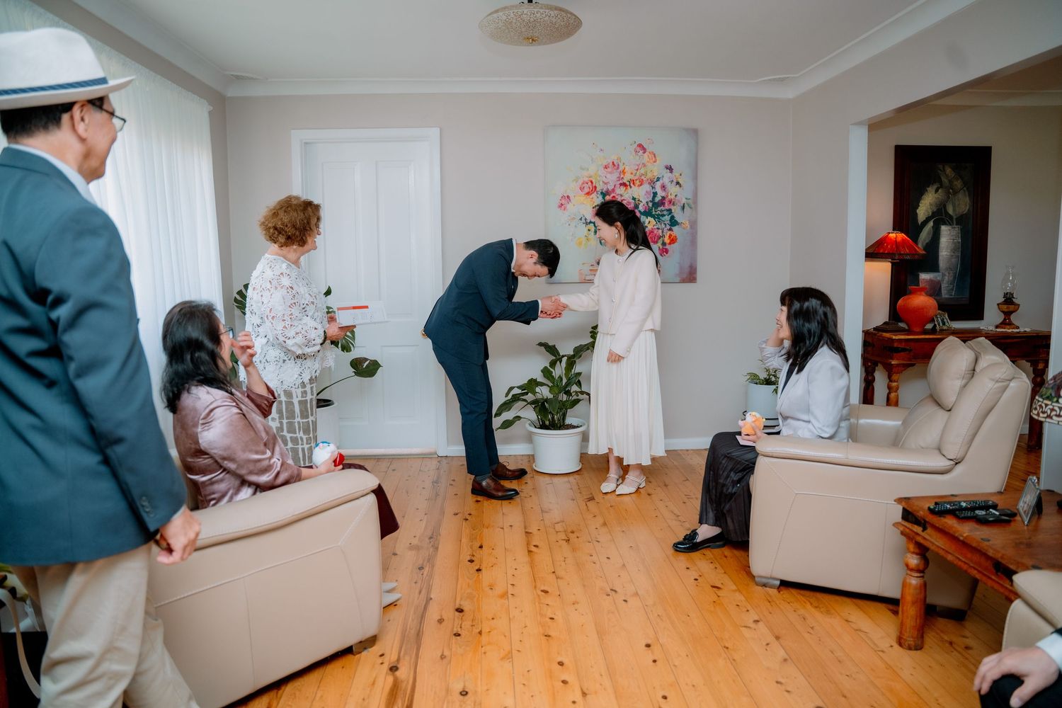 Groom and bride exchange a gift as close family watch - intimate at-home elopement ceremony photography