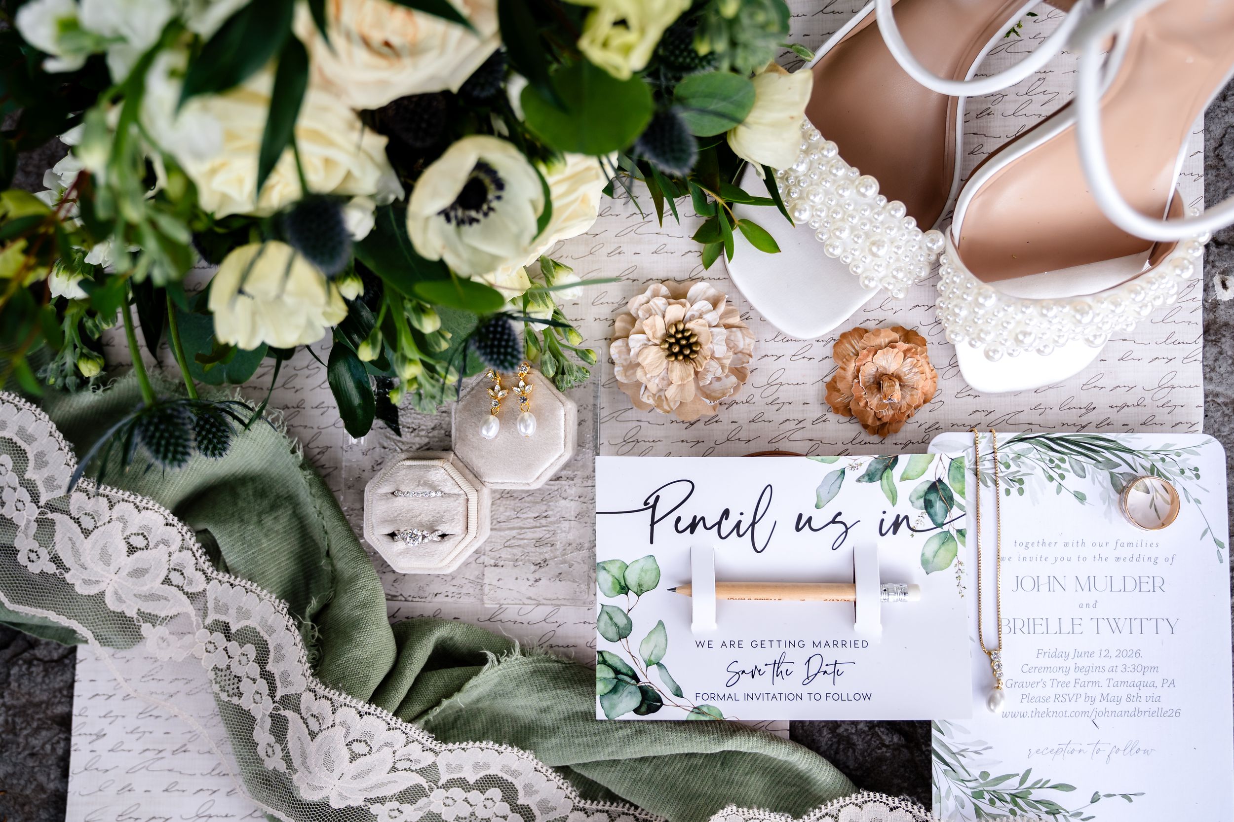 Elegant wedding flat lay with floral bouquet, invitation, rings, and bridal heels.