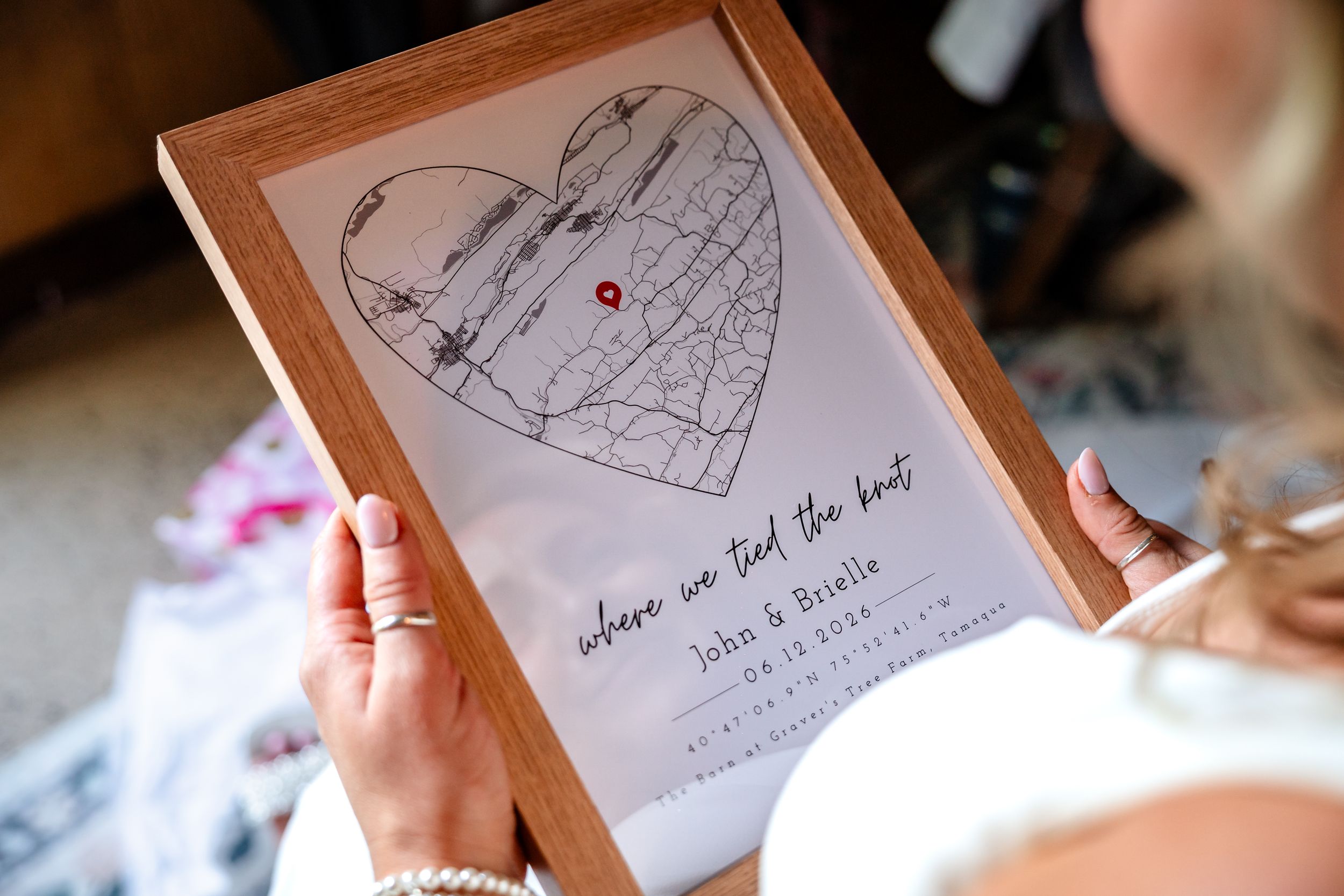 Bride holds framed heart-shaped map gift reading where we tied the knot by John and Rosalie.