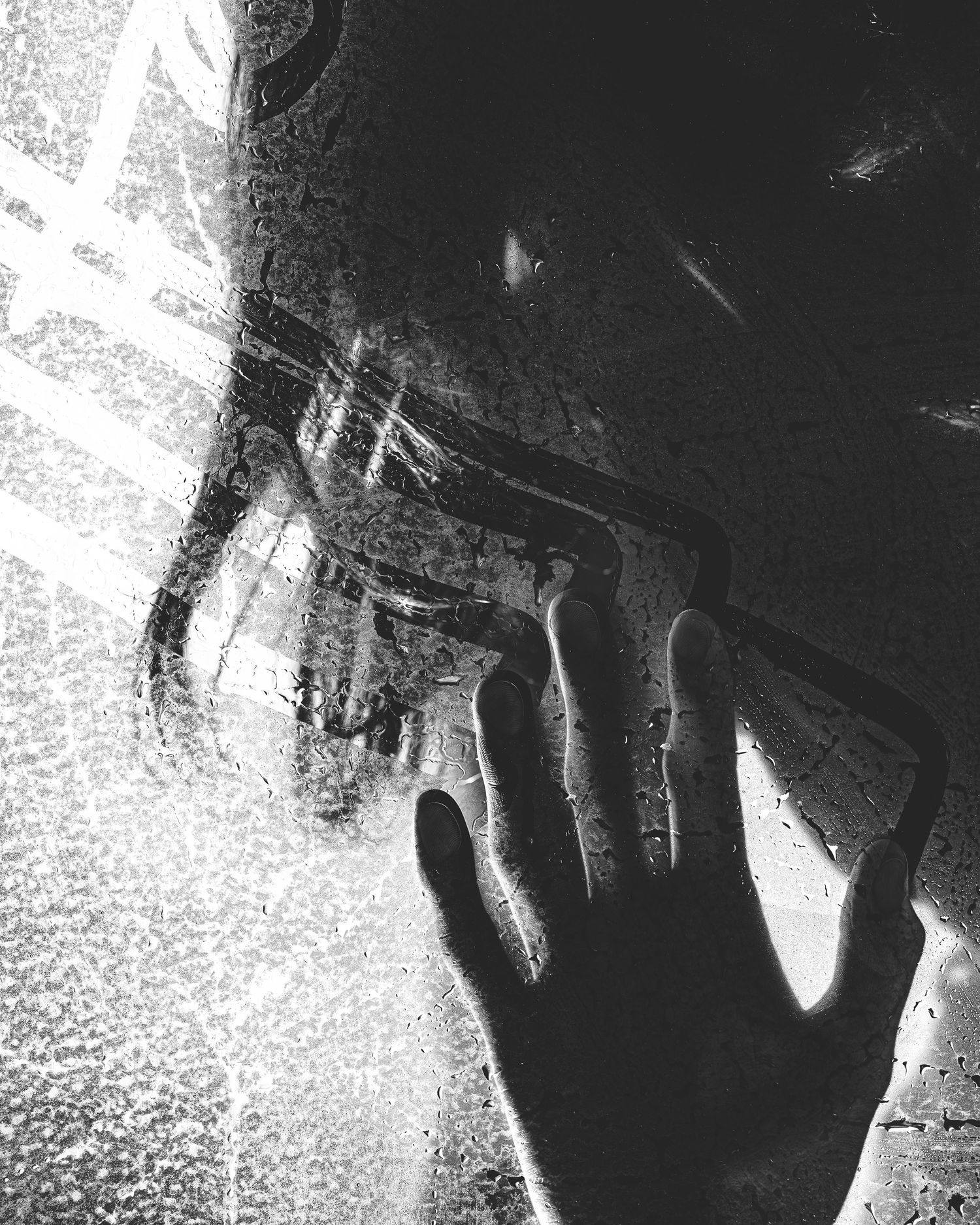 Abstract high-contrast black and white photo of a hand reaching, grainy artistic texture