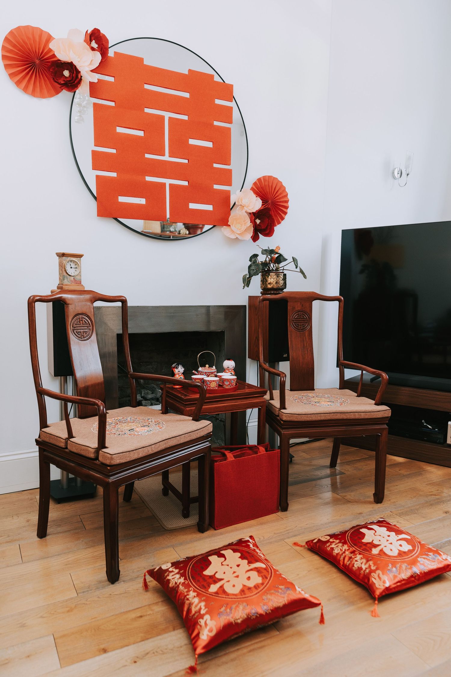 Traditional Chinese wedding tea ceremony setup with red double happiness decor, wooden chairs, and embroidered cushions.